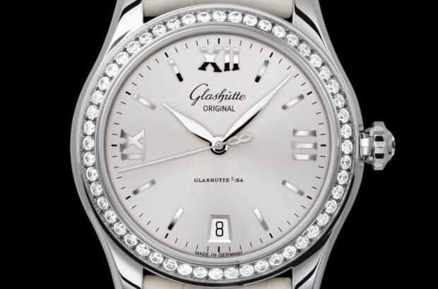 Edelstahl-Gehäuse Poliertes Gehäuse aus Edelstahl mit Saphirglasboden, Lünette mit Brillanten besetzt, Brillant auf Krone 